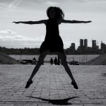 A dynamic black and white silhouette of a woman jumping with arms outstretched in Tallinn, Estonia.