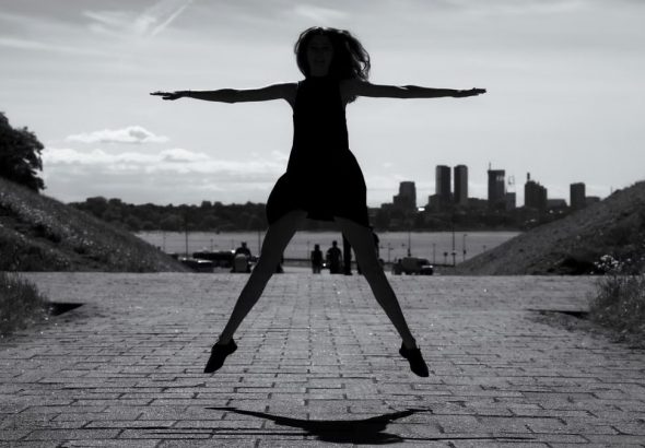 A dynamic black and white silhouette of a woman jumping with arms outstretched in Tallinn, Estonia.