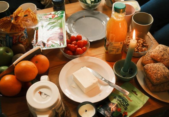 A cozy breakfast spread featuring fresh fruits, bread, and juice, surrounded by warm candlelight.
