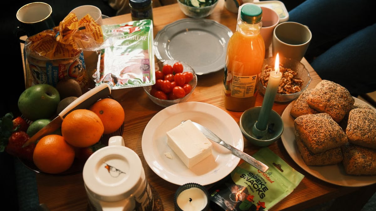 A cozy breakfast spread featuring fresh fruits, bread, and juice, surrounded by warm candlelight.